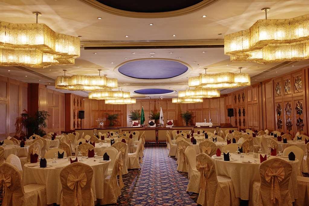 마카렘 아지아드 마카 호텔 메카 시설 사진 The photo shows an elegantly arranged banquet or conference room. There are several round tables covered with light-colored tablecloths and adorned with decorative napkins. The seating is also stylish, with chairs featuring matching coverings. The ro