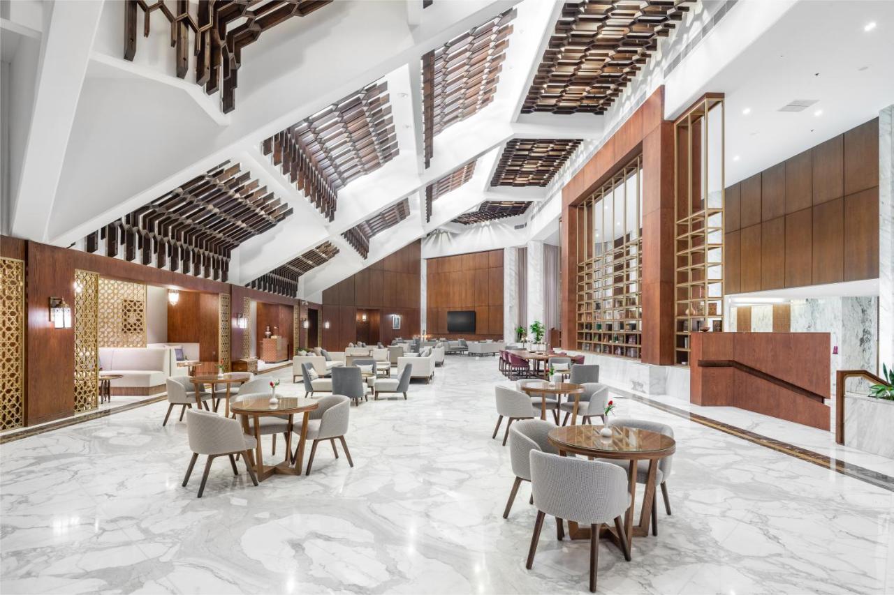 마카렘 아지아드 마카 호텔 메카 외부 사진 The photo shows a spacious and modern interior, likely of a hotel or a large dining area. The design features high ceilings with an interesting architectural style, including a combination of wooden elements and sleek, modern finishes. 

The floor is