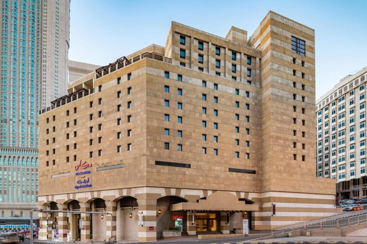 마카렘 아지아드 마카 호텔 메카 외부 사진 The photo shows a multi-story building with a distinctive architectural style. The facade features a combination of textured stone and concrete, giving it a contemporary yet somewhat traditional appearance. The building has multiple windows arranged 