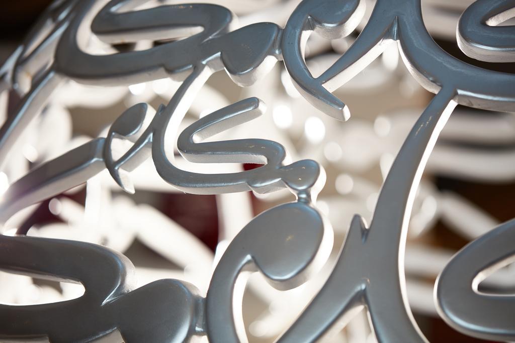 마카렘 아지아드 마카 호텔 메카 외부 사진 The photo shows a close-up of a white, artistic structure or piece of decor that features intricate, stylized lettering. The letters are intertwined and have a fluid, modern design. The focus on the details reveals the elegance of the curves and shap